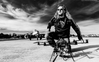 Michael J. Müller hockt auf dem Flugfeld neben seinem Oktokopter – Schwarzweißfoto