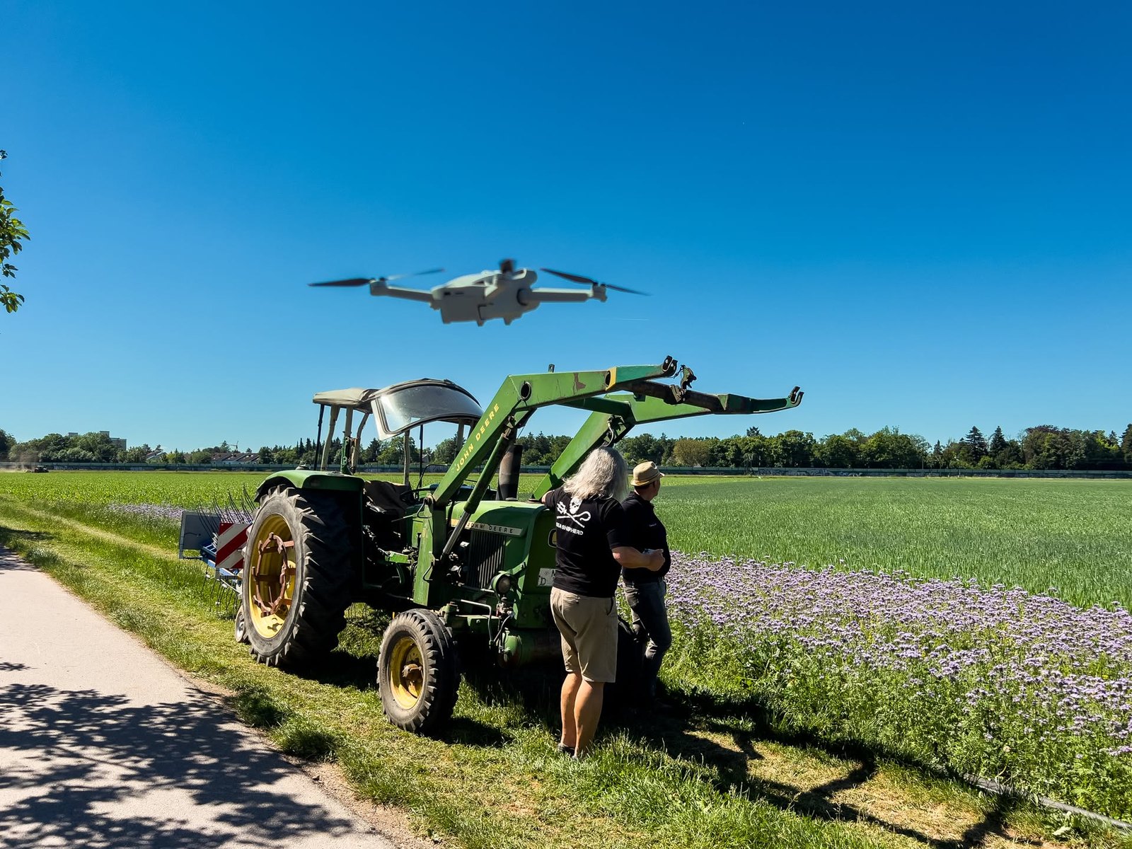 Der Traktor auf dem Feld, darüber die Drohne