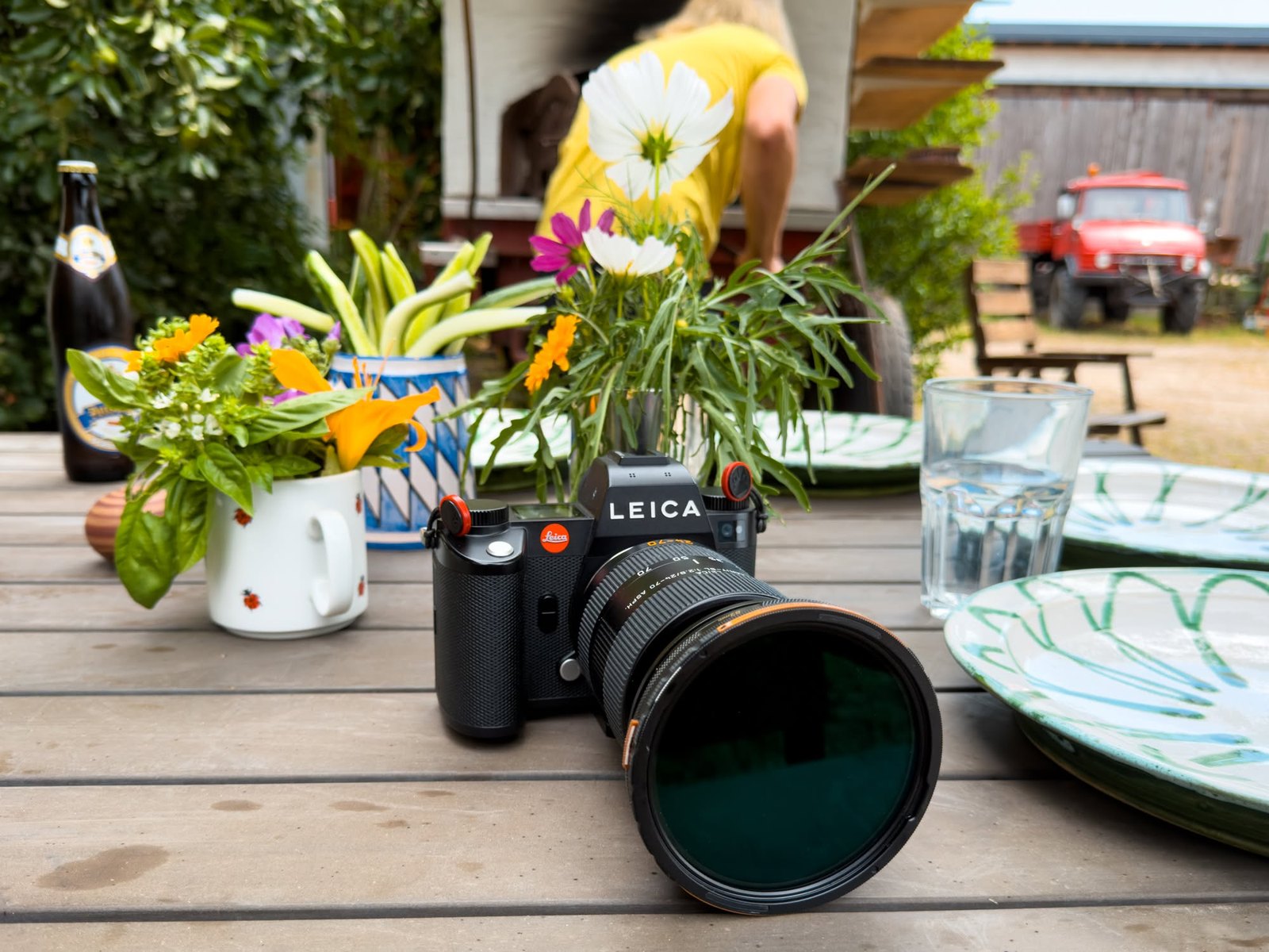 Die Leica neben Blumen und Geschirr auf dem Gartentisch