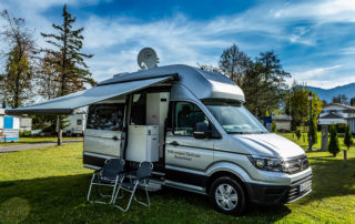 Silberner Campingbus mit Sat-Antenne und Markise vor Bergkulisse – Foto- und Videoshooting für Kathrein Digital Systems