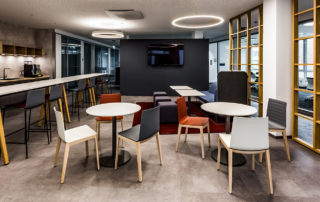 Kantine mit Holztischen, Stühlen und Ringleuchte – Fotoshooting bei Pieris für office4you