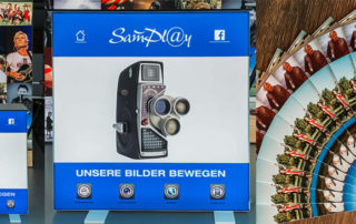 SamPlay-Infostand mit alter Filmkamera und Fächer aus Postkarten – Tag der offenen Tür bei Birmoser Werbetechnik