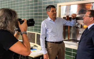 Fotografin bei der Arbeit, zwei Männer im Sudhaus – Slow-Brewing-Audit bei der Privatbrauerei Schweiger