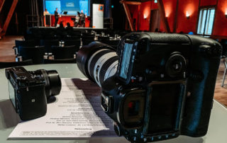 Kameras auf dem Tisch vor der Bühne – Fotoshooting bei der Auftaktveranstaltung „Werte bs“ der Stiftung Bildungspakt Bayern