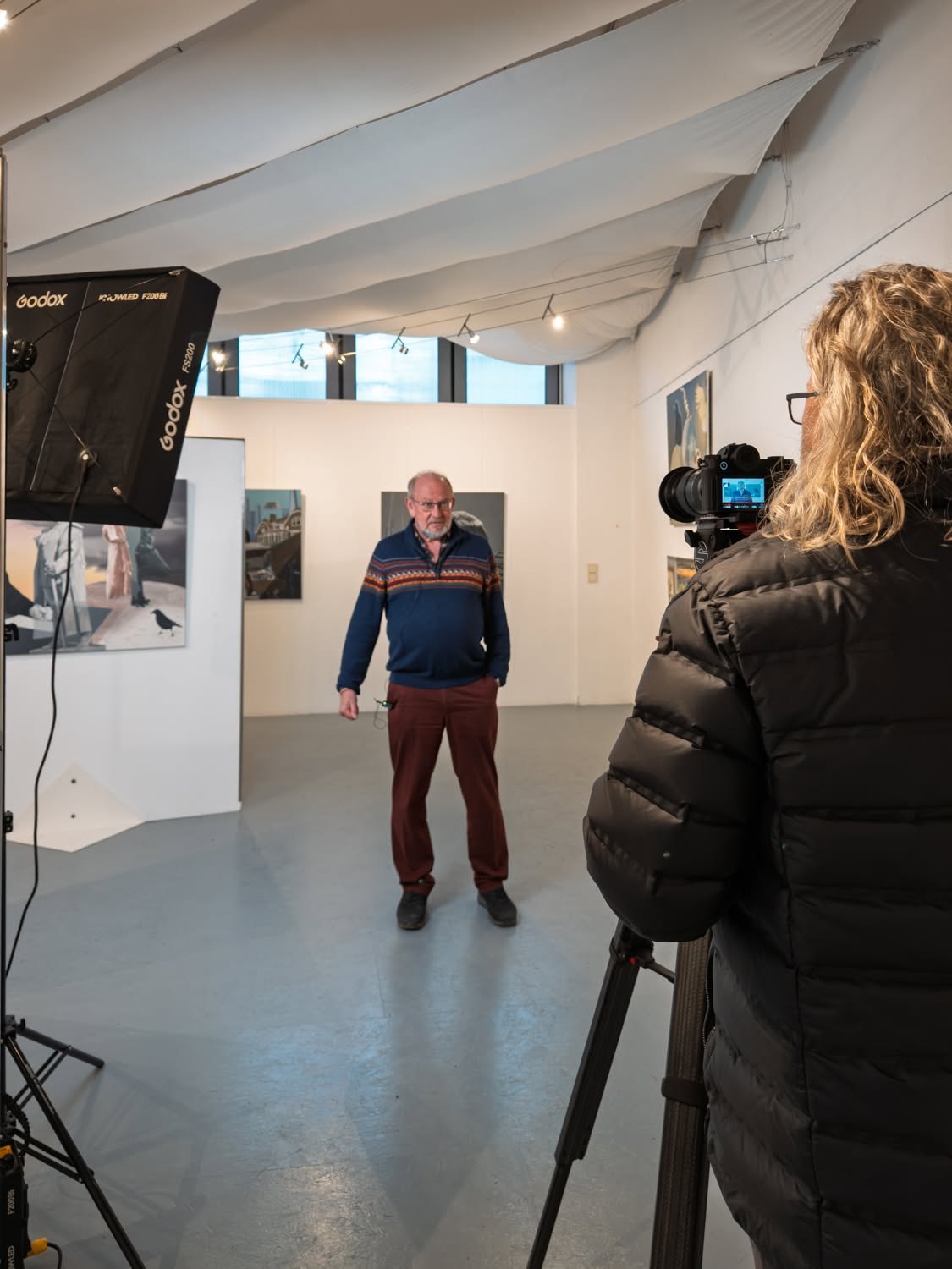 Interviewsituation im Kunstverein: Der Gesprächspartner steht zwischen den Bildern, die Kamera läuft